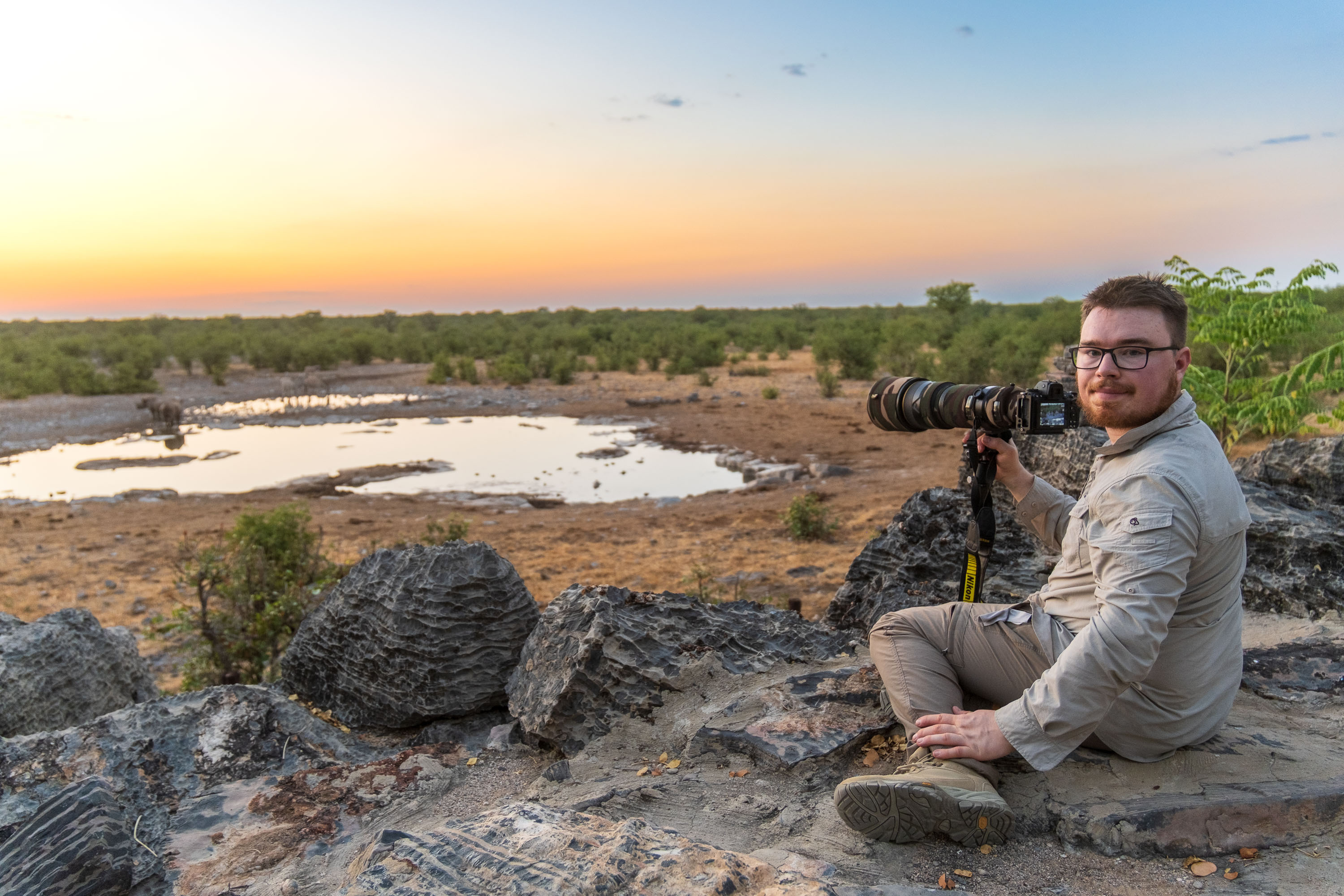 Felix Lukas Kübler mit Kamera in einer Landschaft bei Sonnenuntergang.